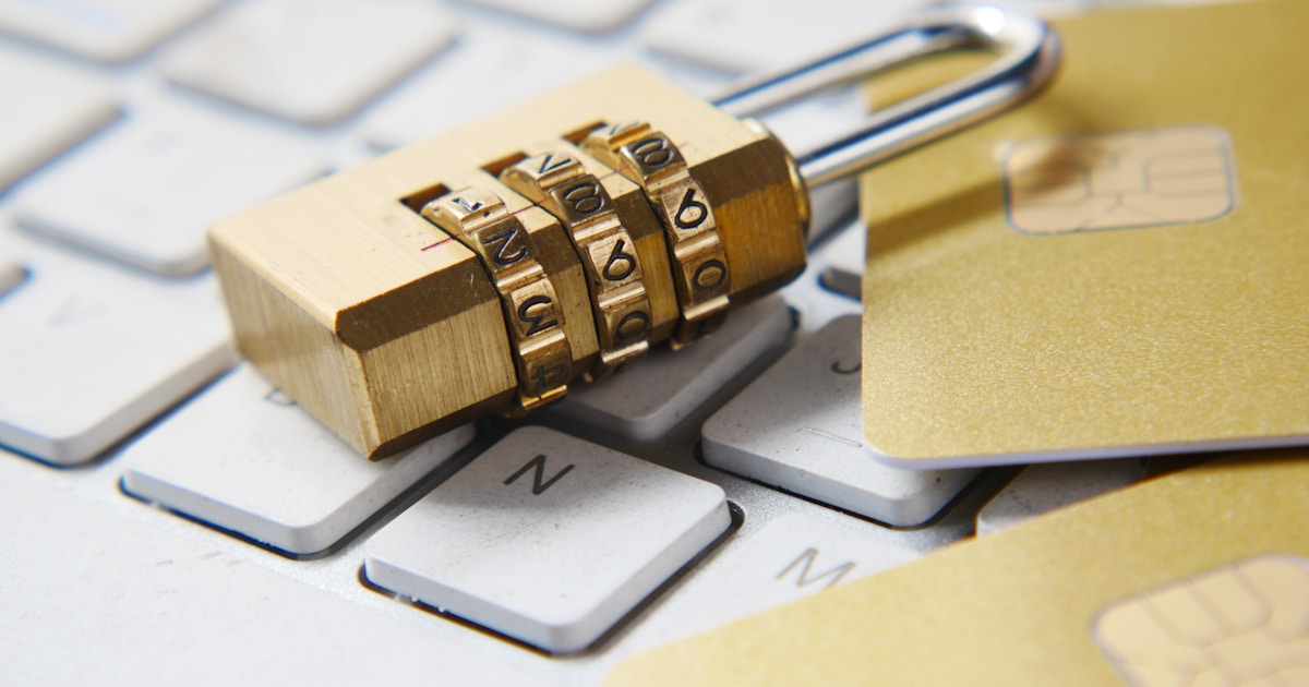 南京錠とICチップ付きのカードがキーボードの上に置かれた、個人番号カードと特定個人情報の管理を象徴する画像